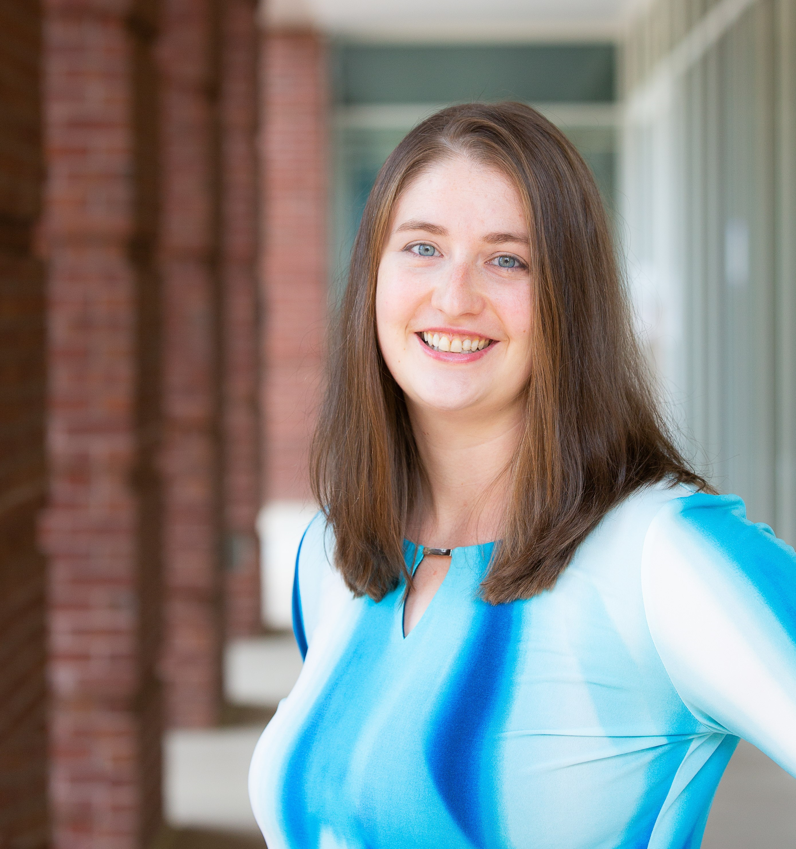 Martina smiling and wearing a blue shirt while standing outside of the Student Health and Wellness building