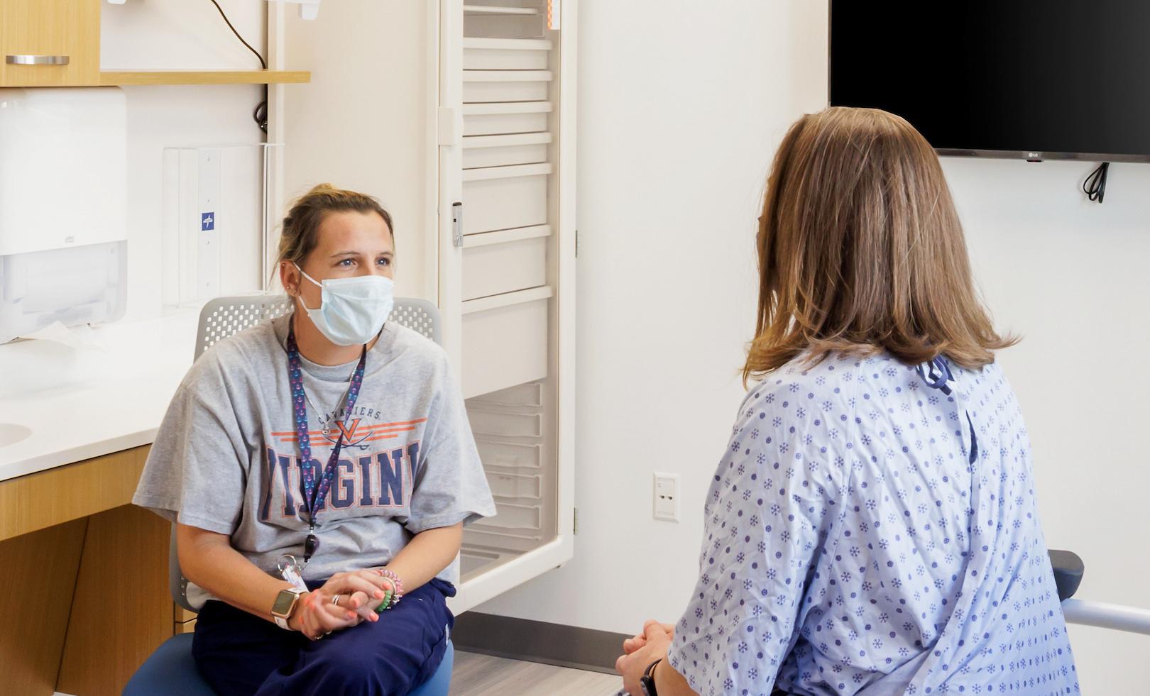 A health care provider and a patient sit in a light-filled exam room.