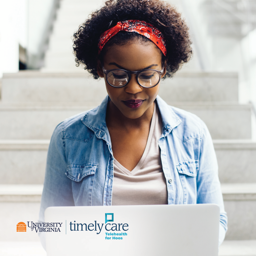 A Black woman wears glasses, a red headband, and jean shirt while sitting on steps. She is looking down at her laptop. The UVA TimelyCare logo is visible at the bottom.