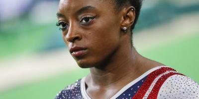 Gymnast Simone Biles wearing a red and blue uniform.