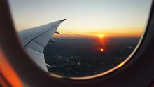 A view out of a plane window as the sun is setting on a city.