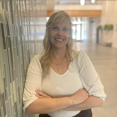 Sonja leaning against a mosaic wall within the Student Health and Wellness Building